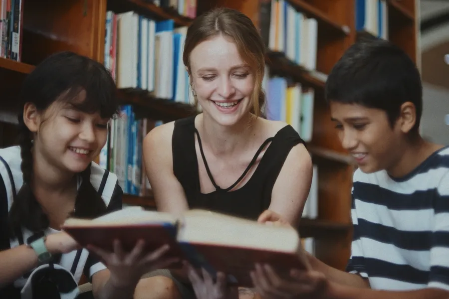 A teacher reading with two pupils